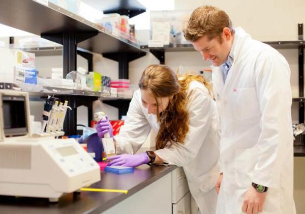 Young male and female students in white lab coats working in a science lab