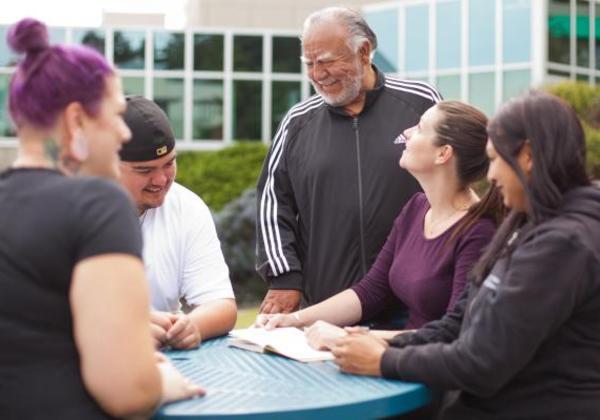 Male and female students together outside with an older man