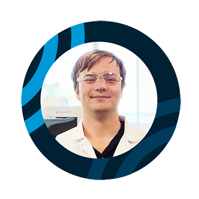 Smiling young male student wearing glasses and a white lab coat